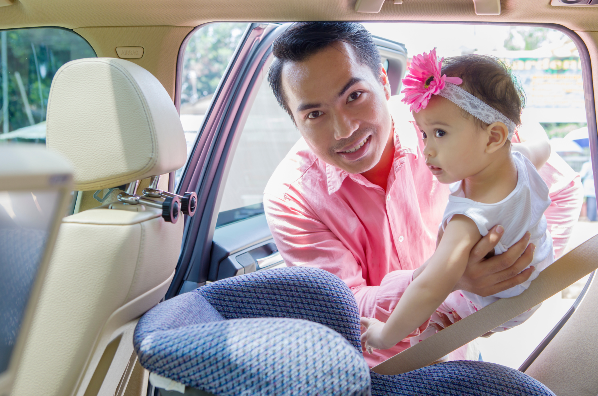 Une personne met un enfant d’âge préscolaire dans un siège d’auto orienté vers l’arrière sur le siège arrière d’un véhicule.